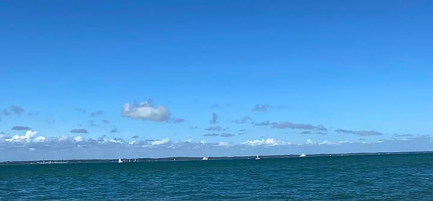 The Solent from the beach at Fort Victoria: blue water, a line of the mainland and a few white sails on the horizon
